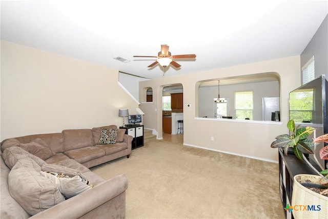 living room with ceiling fan with notable chandelier and light carpet