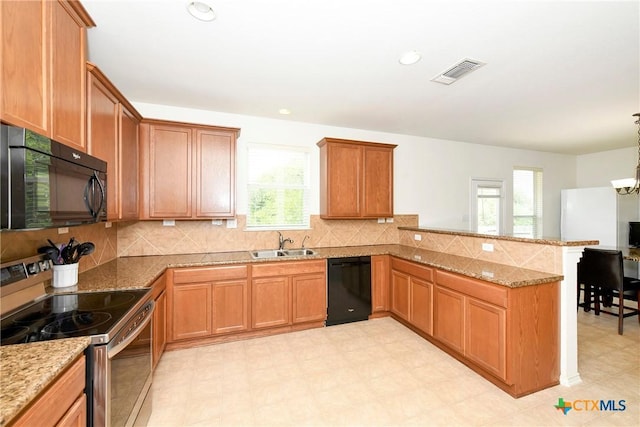 kitchen with kitchen peninsula, pendant lighting, sink, light stone counters, and black appliances