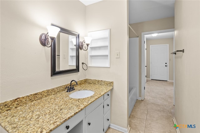 bathroom with a tub to relax in, vanity, and tile patterned floors