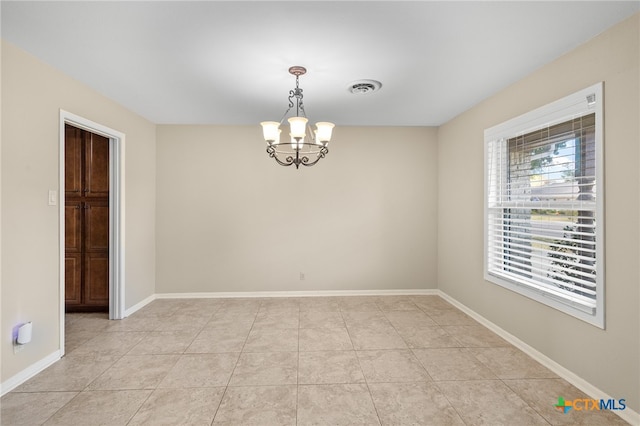 spare room with an inviting chandelier and light tile patterned floors