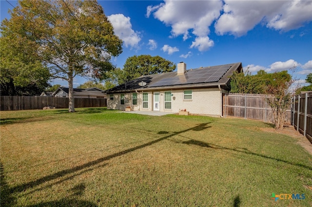 rear view of house featuring a patio, solar panels, and a lawn