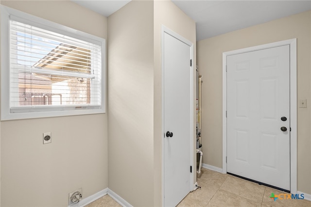 clothes washing area with electric dryer hookup and light tile patterned floors