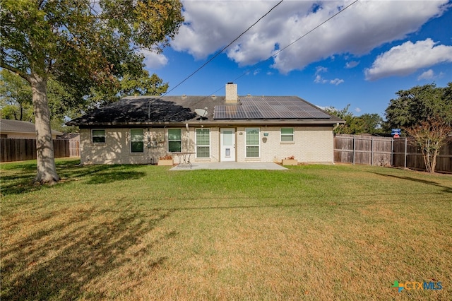 back of house featuring solar panels, a lawn, and a patio