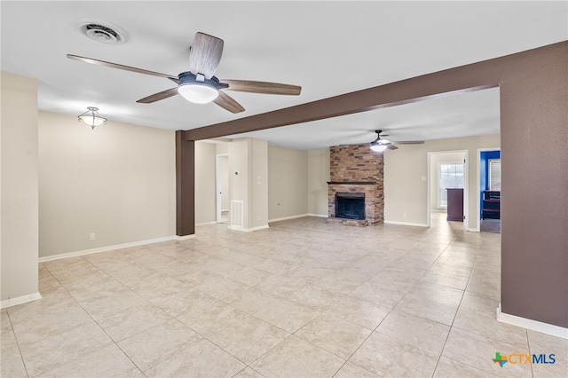 unfurnished living room with a stone fireplace, light tile patterned floors, and ceiling fan