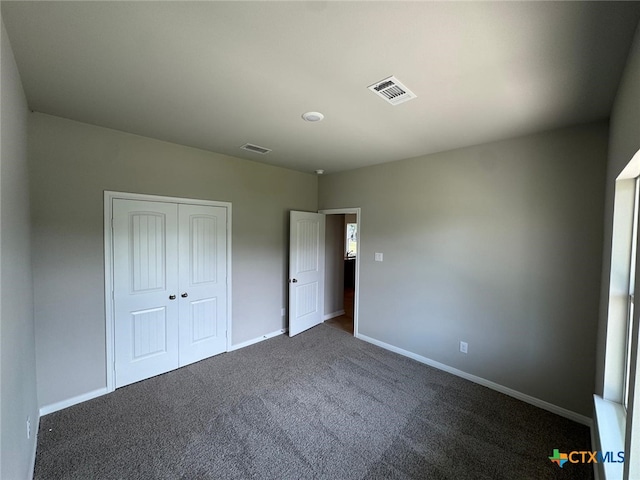 607 W Bayshore Dr, Palacios, TX 77465 - unfurnished bedroom with a closet, visible vents, baseboards, and dark colored carpet