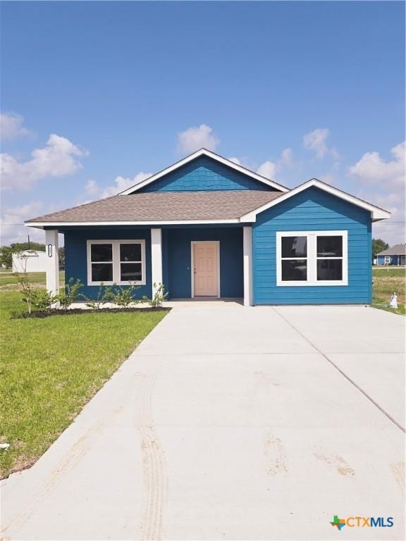 607 W Bayshore Dr, Palacios, TX 77465 - view of front of home with concrete driveway, roof with shingles, and a front lawn