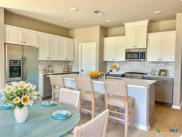 607 W Bayshore Dr, Palacios, TX 77465 - kitchen with a sink, a kitchen island with sink, visible vents, backsplash, and appliances with stainless steel finishes