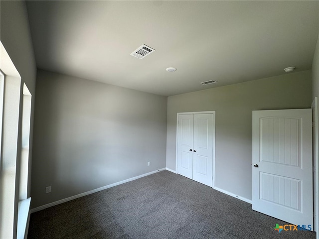 607 W Bayshore Dr, Palacios, TX 77465 - unfurnished bedroom with baseboards, a closet, visible vents, and dark carpet