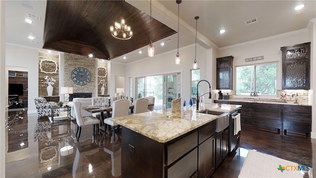 kitchen with a stone fireplace, sink, an island with sink, and a healthy amount of sunlight