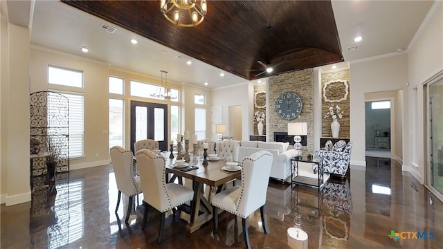 dining room featuring a towering ceiling, a stone fireplace, and a notable chandelier