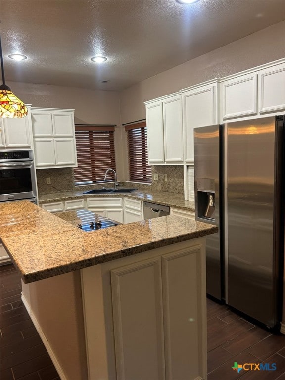 kitchen with sink, tasteful backsplash, light stone countertops, pendant lighting, and appliances with stainless steel finishes