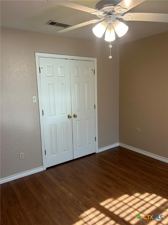 unfurnished bedroom featuring ceiling fan, dark hardwood / wood-style floors, and a closet