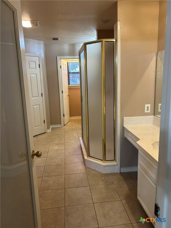 bathroom featuring walk in shower, vanity, a textured ceiling, and tile patterned floors