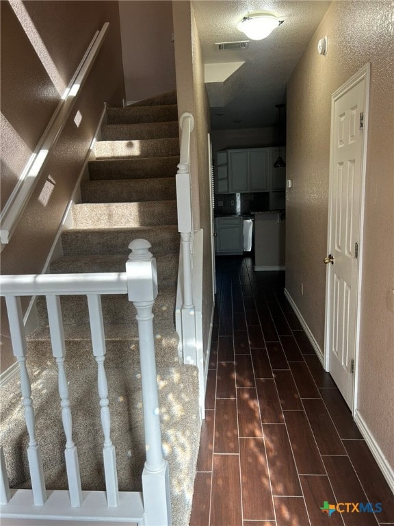 stairs featuring a textured ceiling