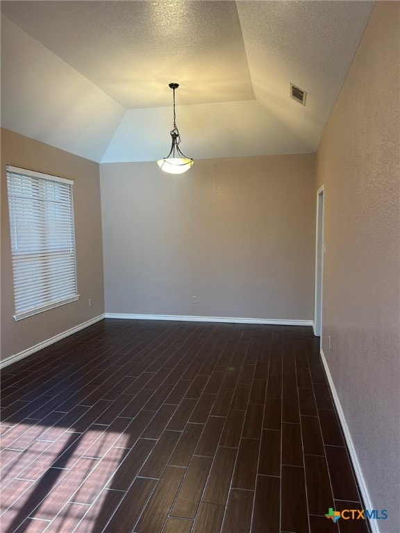 spare room featuring vaulted ceiling, a textured ceiling, and dark hardwood / wood-style flooring