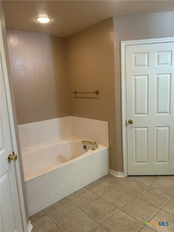 bathroom with a washtub, a textured ceiling, and tile patterned floors