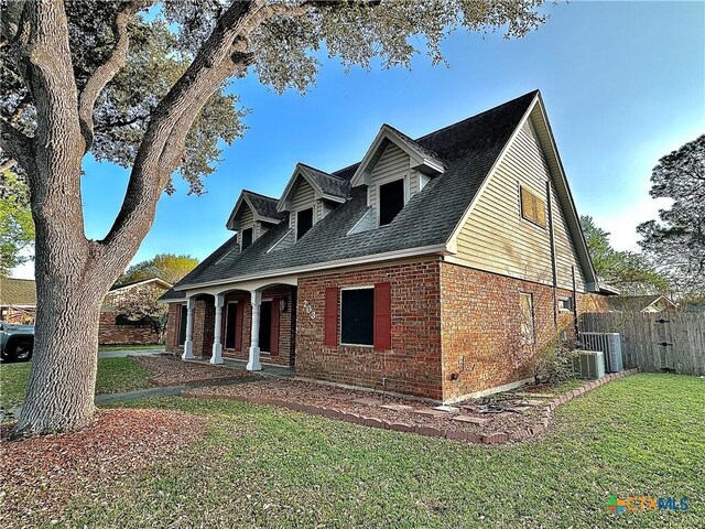 203 Hampshire St, Victoria, TX 77904 - cape cod-style house featuring brick siding, roof with shingles, and central air condition unit