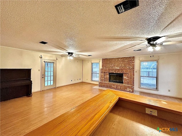 203 Hampshire St, Victoria, TX 77904 - unfurnished living room with ceiling fan, wood finished floors, a textured ceiling, and a brick fireplace