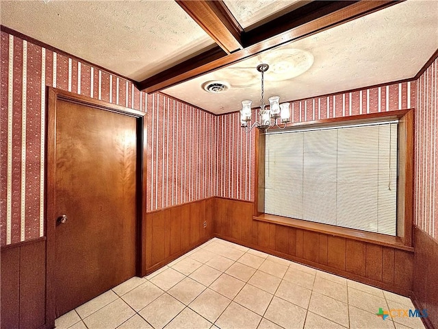 203 Hampshire St, Victoria, TX 77904 - unfurnished dining area featuring a chandelier, wallpapered walls, a textured ceiling, light tile patterned floors, and a wainscoted wall