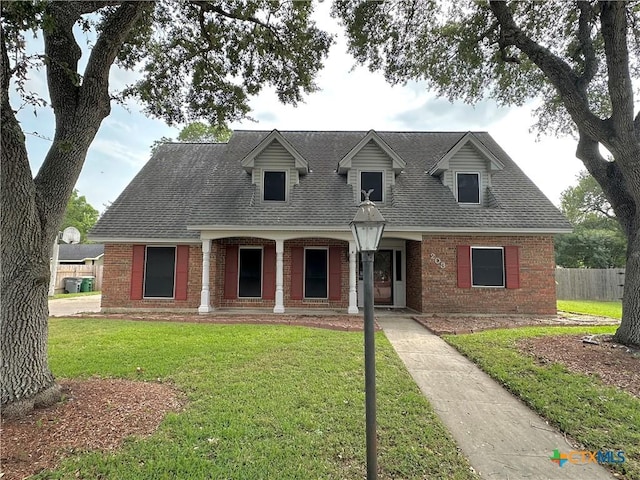 203 Hampshire St, Victoria, TX 77904 - new england style home featuring brick siding, a shingled roof, and covered porch