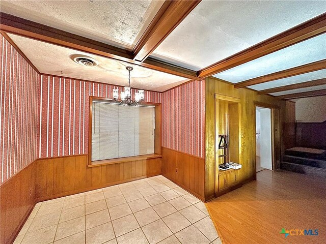 203 Hampshire St, Victoria, TX 77904 - unfurnished dining area with beam ceiling, a chandelier, wood walls, a textured ceiling, and wainscoting