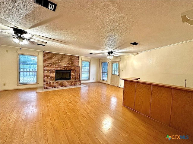 203 Hampshire St, Victoria, TX 77904 - unfurnished living room with ceiling fan, a textured ceiling, light wood-style flooring, and a fireplace