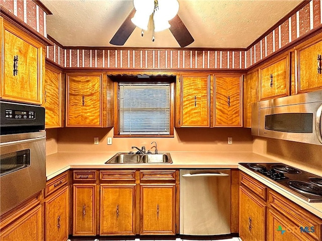 203 Hampshire St, Victoria, TX 77904 - kitchen with appliances with stainless steel finishes, a textured ceiling, a sink, brown cabinetry, and light countertops