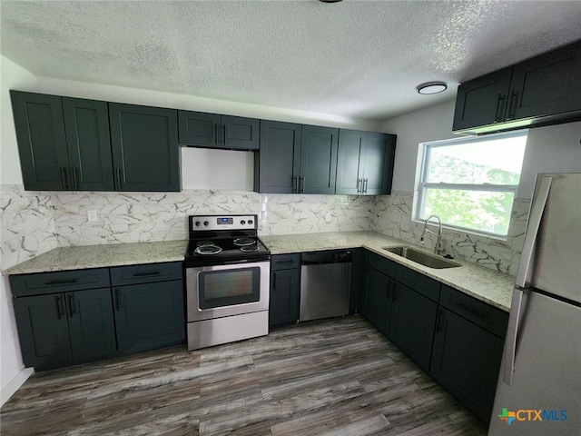 kitchen with sink, stainless steel appliances, tasteful backsplash, dark hardwood / wood-style floors, and a textured ceiling