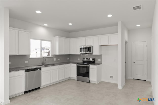 kitchen featuring white cabinetry, sink, stainless steel appliances, dark stone countertops, and decorative backsplash