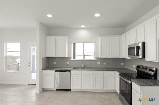 kitchen featuring white cabinets, appliances with stainless steel finishes, dark stone countertops, and sink