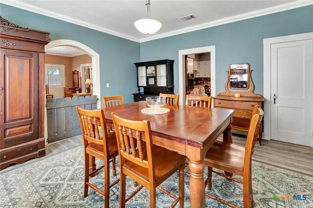 304 W Putnam, Ganado, TX 77962 - dining room featuring arched walkways, crown molding, and light wood-type flooring