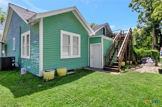 304 W Putnam, Ganado, TX 77962 - back of house with roof with shingles, cooling unit, a lawn, and stairway