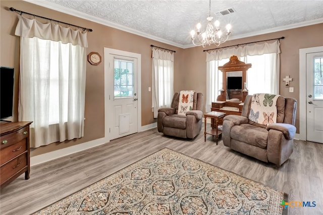 living area featuring light hardwood / wood-style floors, a healthy amount of sunlight, an inviting chandelier, and crown molding