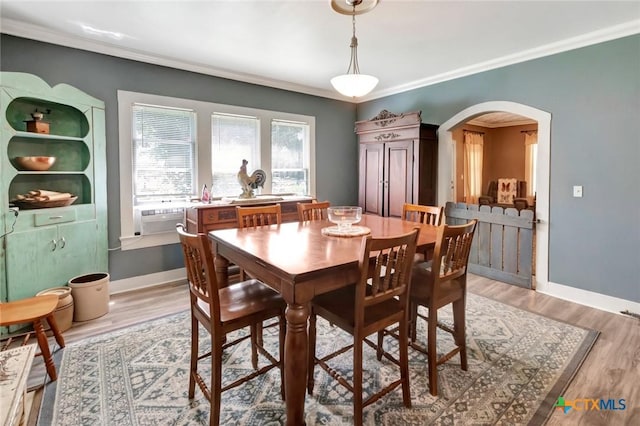 304 W Putnam, Ganado, TX 77962 - dining area with arched walkways, crown molding, light wood-style flooring, baseboards, and cooling unit