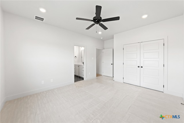 unfurnished bedroom with ceiling fan, light colored carpet, connected bathroom, and a closet