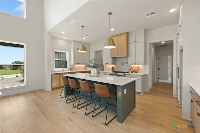 kitchen with pendant lighting, a center island, backsplash, light hardwood / wood-style flooring, and white cabinetry