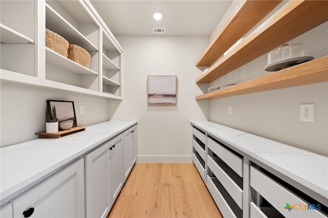 bar featuring white cabinets, light wood-type flooring, and light stone counters