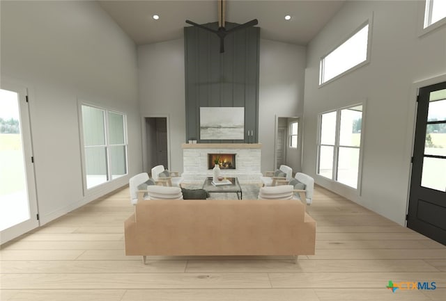 living room featuring a fireplace, high vaulted ceiling, and light hardwood / wood-style floors