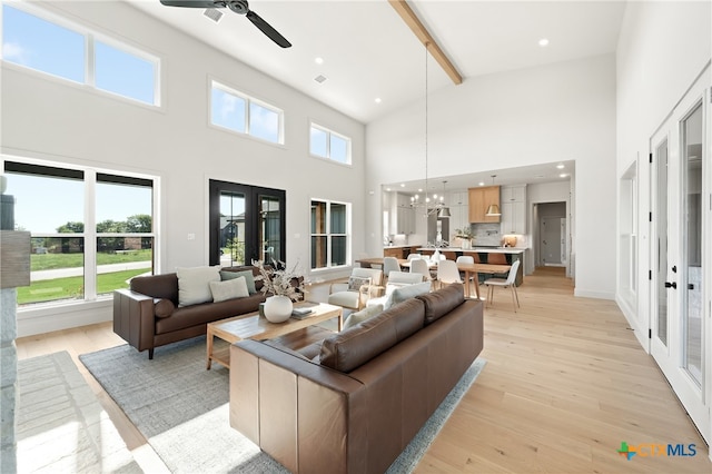 living room with high vaulted ceiling, french doors, ceiling fan with notable chandelier, beamed ceiling, and light hardwood / wood-style floors