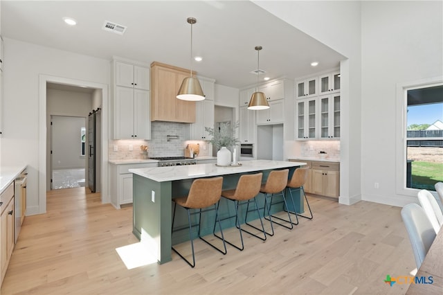 kitchen featuring decorative backsplash, white cabinets, a center island, light hardwood / wood-style floors, and hanging light fixtures