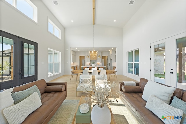 living room featuring a chandelier, light hardwood / wood-style flooring, high vaulted ceiling, and french doors