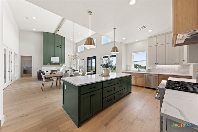 kitchen featuring light stone counters, stainless steel appliances, a kitchen island, white cabinetry, and hanging light fixtures