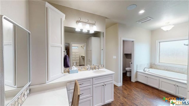158 Sendera Loop, Victoria, TX 77904 - bathroom with toilet, wood finished floors, a walk in closet, vanity, and a bath