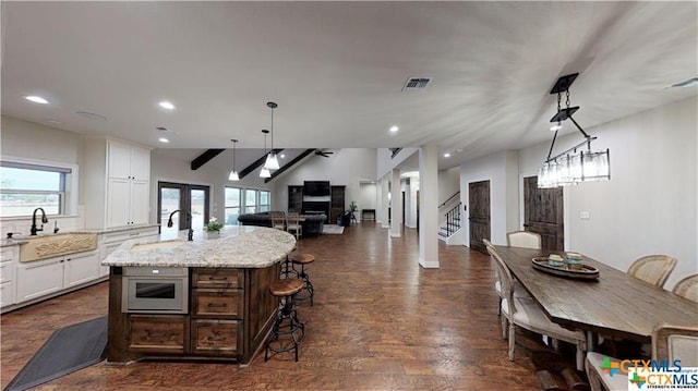 158 Sendera Loop, Victoria, TX 77904 - kitchen with a sink, a kitchen island with sink, white cabinetry, open floor plan, and light stone counters