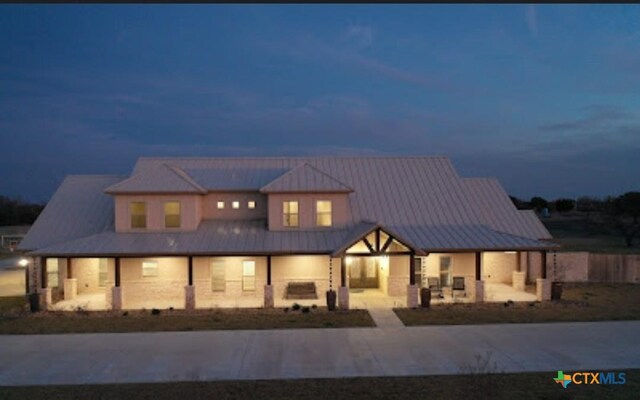 158 Sendera Loop, Victoria, TX 77904 - back of house at twilight with a porch, a standing seam roof, and metal roof