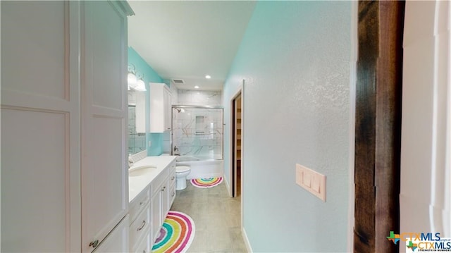 158 Sendera Loop, Victoria, TX 77904 - full bath featuring toilet, vanity, a textured wall, enclosed tub / shower combo, and tile patterned floors