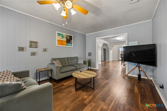 living room with dark wood-type flooring, ornamental molding, a textured ceiling, and ceiling fan