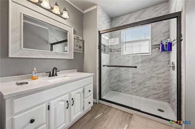 bathroom with vanity, hardwood / wood-style flooring, a shower with door, and crown molding