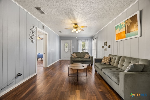 living room with wood walls, ceiling fan, dark hardwood / wood-style floors, a textured ceiling, and crown molding