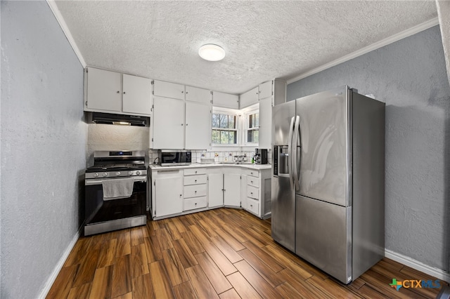 kitchen with white cabinets, stainless steel appliances, ornamental molding, and dark hardwood / wood-style floors